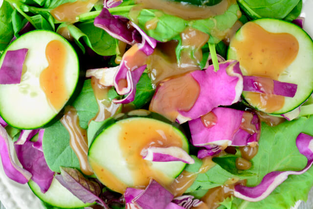 Close up view of lettuce, red cabbage, and cucumbers drizzled with  balsamic vinaigrette