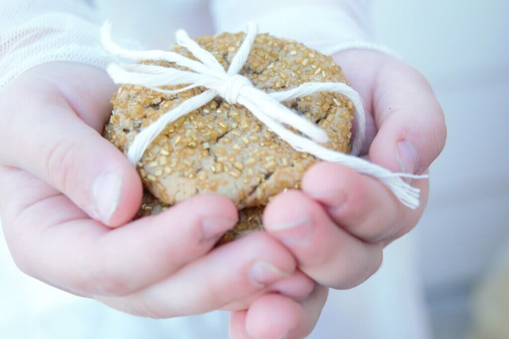 Hands cupped and holding a stack of ginger cookies tied with white yarn