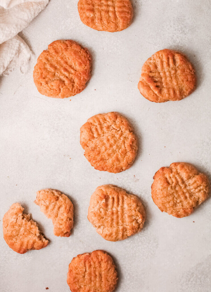 Top view of peanut butter maple cookies with one broken and white tea towel