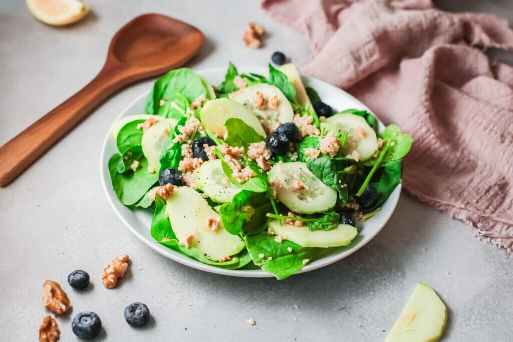 Kidney friendly Summer salad with pink tea towel and wooden spoon and blueberries