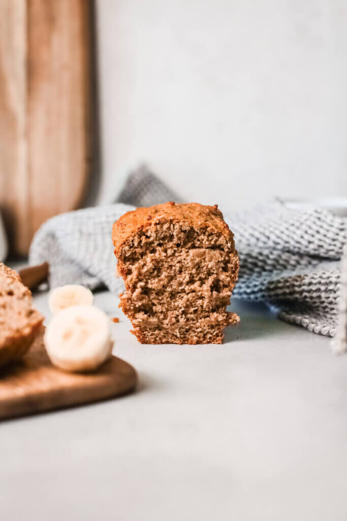 Side view of loaf of vegan banana bread with a blue tea towel and wooden board in the background