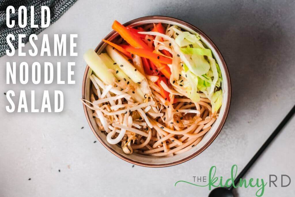 Top view vegan asian noodle salad in a black bowl with a black spoon and green dish towel
