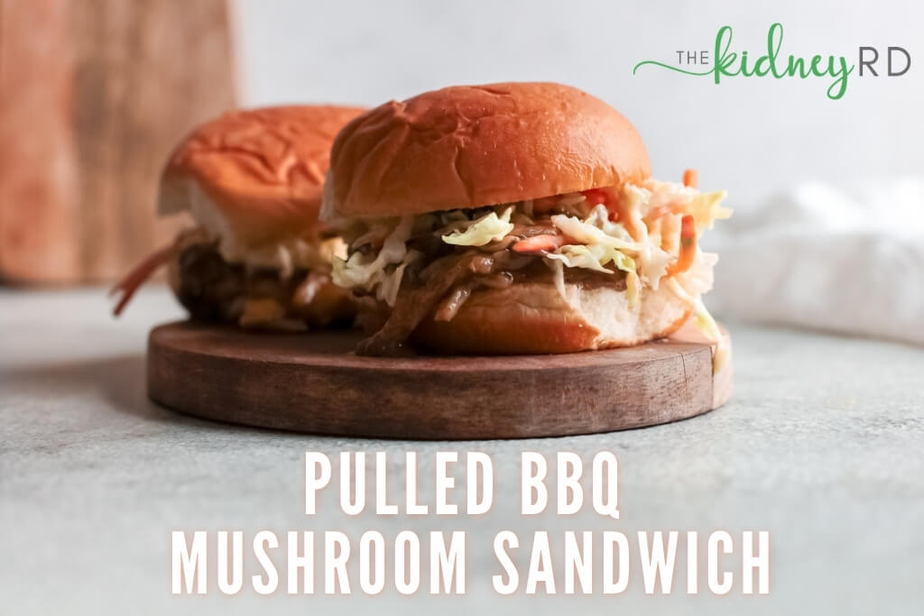 Zoomed out shot of 2 BBQ mushroom sandwiches on a wooden board with wooden cutting board and white tea towel in the background