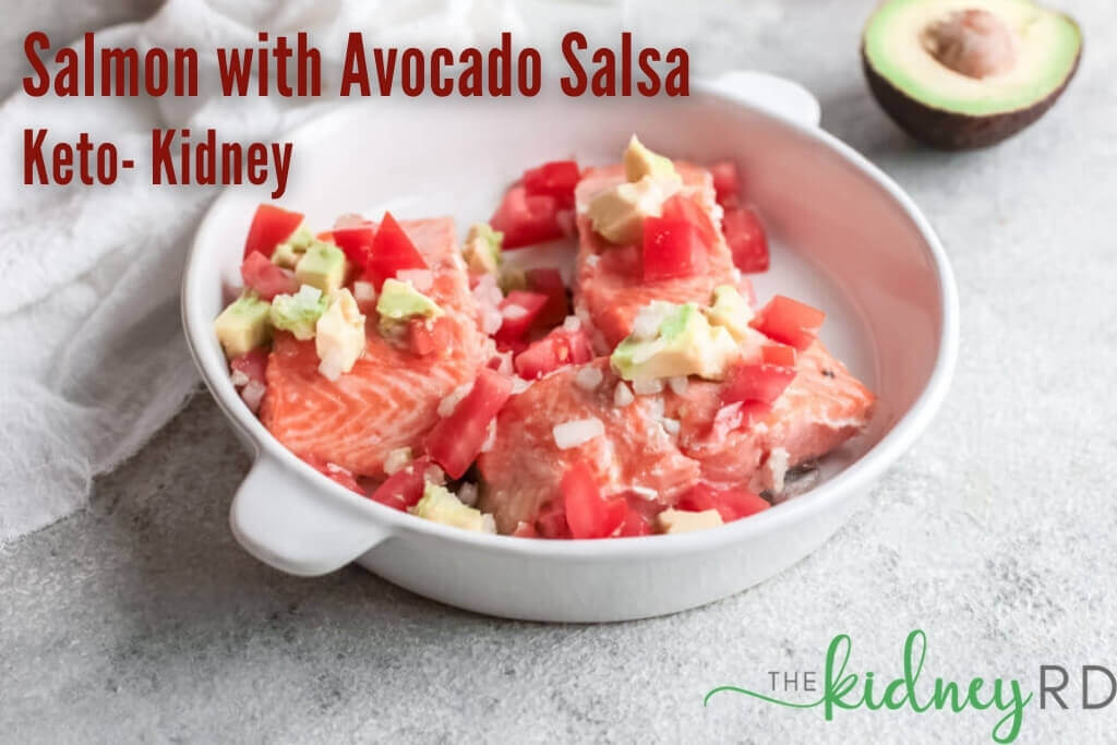 Keto salmon with avocado salsa on a white plate with white tea towel and half of an avocado in the background