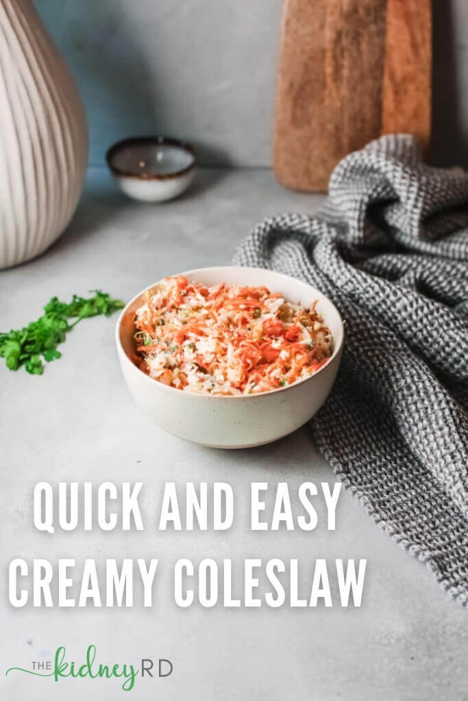 Easy vegan coleslaw in a white bowl with a grey tea towel, parsley, small bowl and wooden cutting board in the background