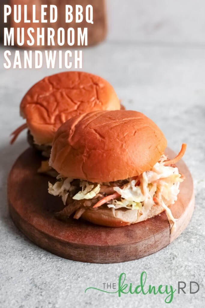 Overhead angled view of two pulled BBW mushroom sandwiches on a wooden board with slaw