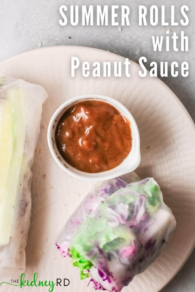 Top view of summer rolls on white plate with small white bowl of peanut sauce