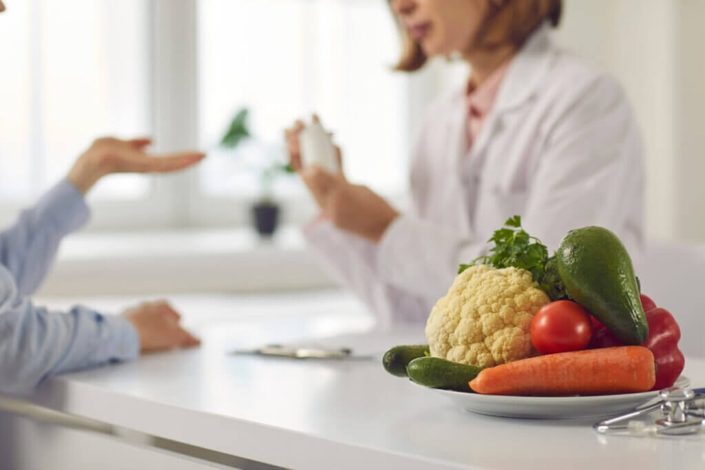 Dietitian meeting with a patient holding a bottle with a plate of vegetables next to her