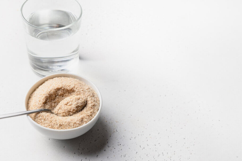 Picture of powdered fiber supplement in a white bowl with a glass of water next to it
