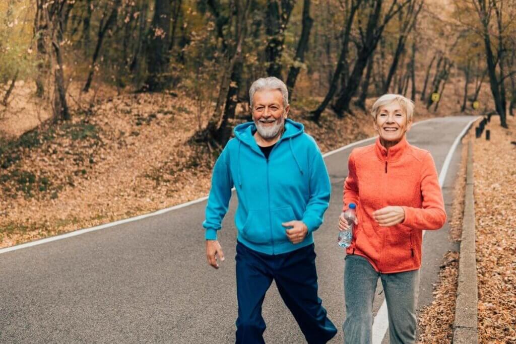 Older couple walking for exercise on road with fall foliage in the background