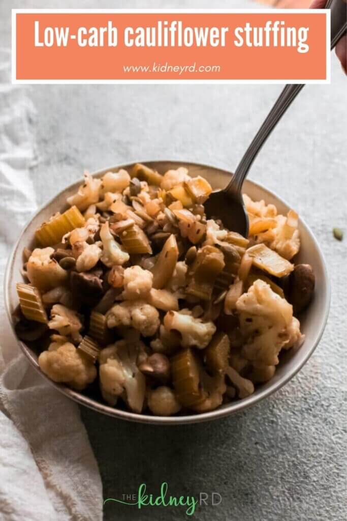 close up view of low carb cauliflower stuffing in a white bowl with a person spooning some out and a white tea towel next to the bowl