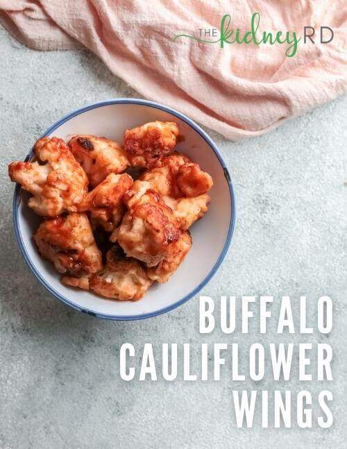 Overhead shot of buffalo cauliflower wings in a white bowl with a pink tea towel next to it