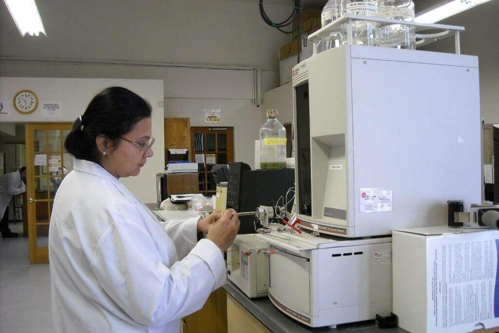 Woman in a white lab coat in a lab looking at specimen