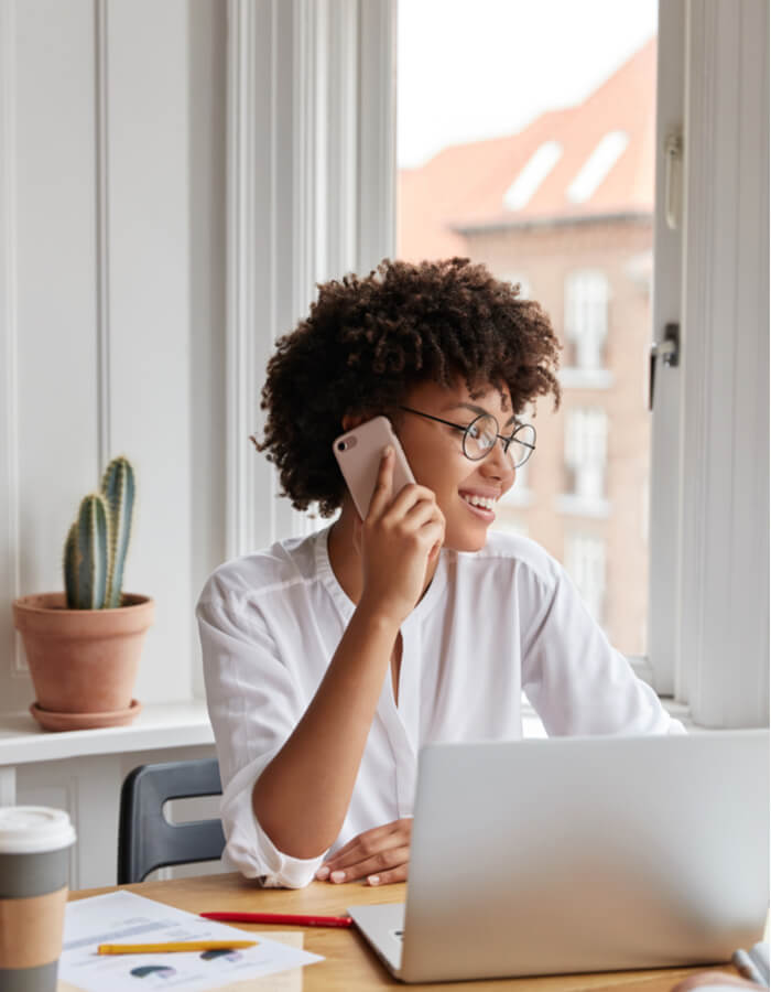 woman talking on her phone at a laptop