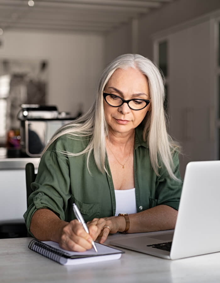 woman at her laptop taking notes