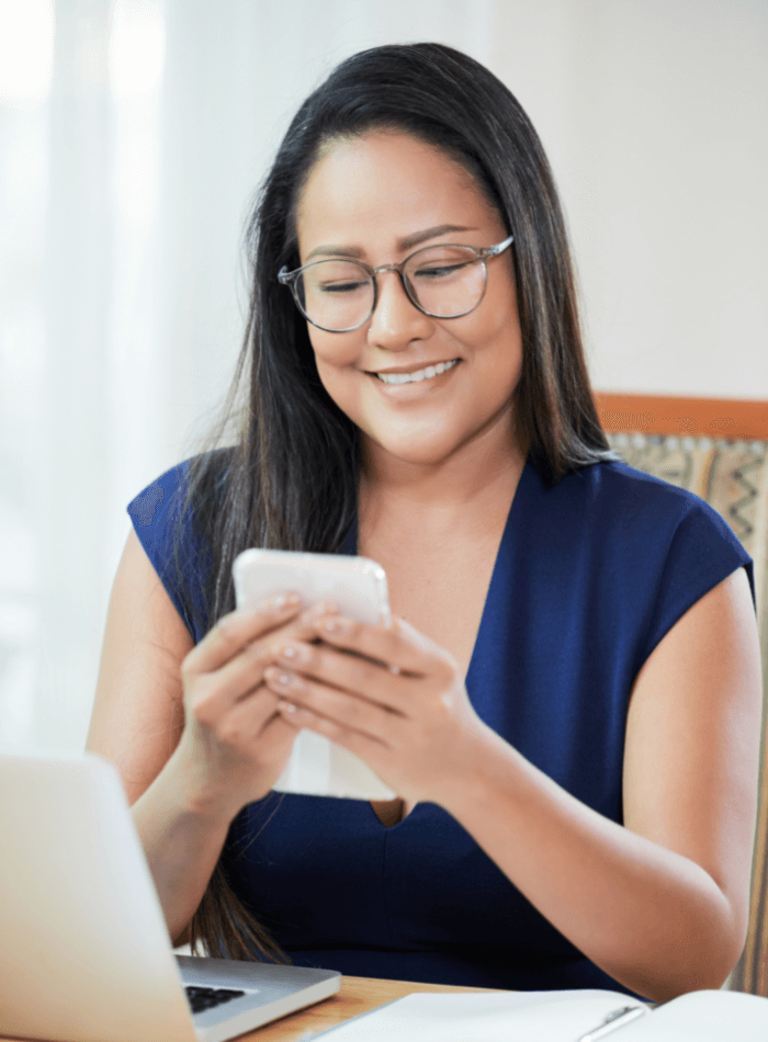 lady checking her phone while sitting at her laptop