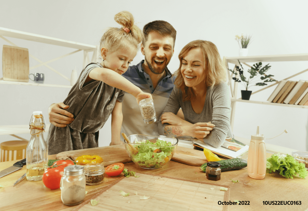 A happy couple involving their daughter in making a salad together as an illustration of fun and stress-free living with PKD in the family
