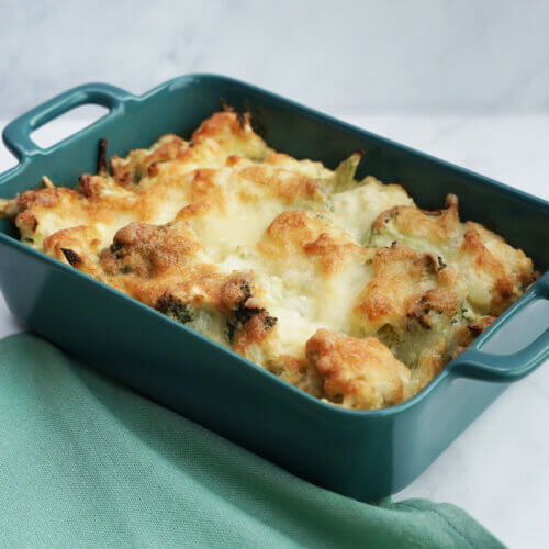 Broccoli and cauliflower gratin topped with melted and browned cheese in a blue casserole dish