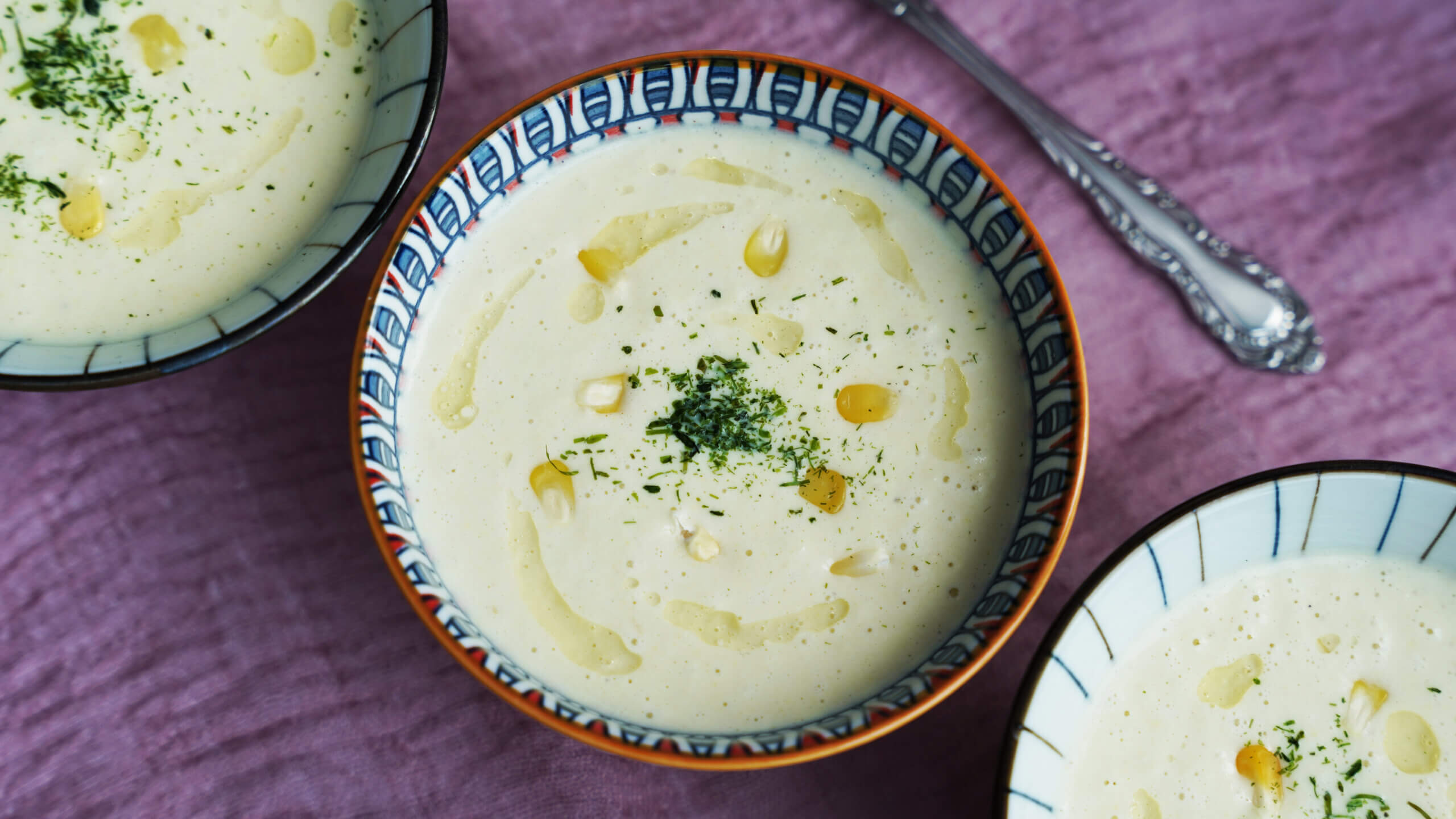 Three bowls of Low Carb Cauliflower Corn Chowder garnished with parsley and a drizzle of olive oil