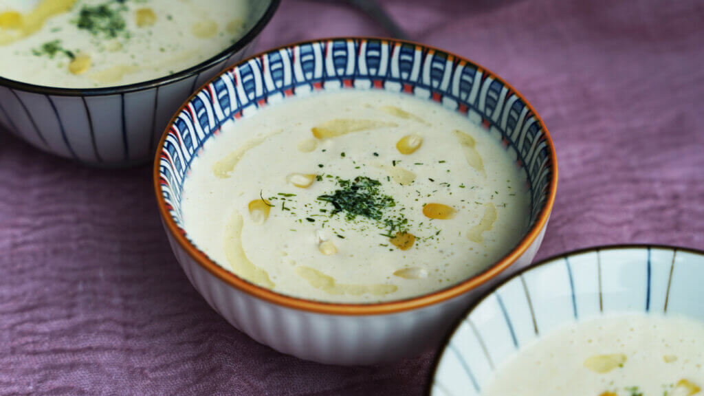 Three bowls of Low Carb Cauliflower Corn Chowder garnished with parsley and a drizzle of olive oil