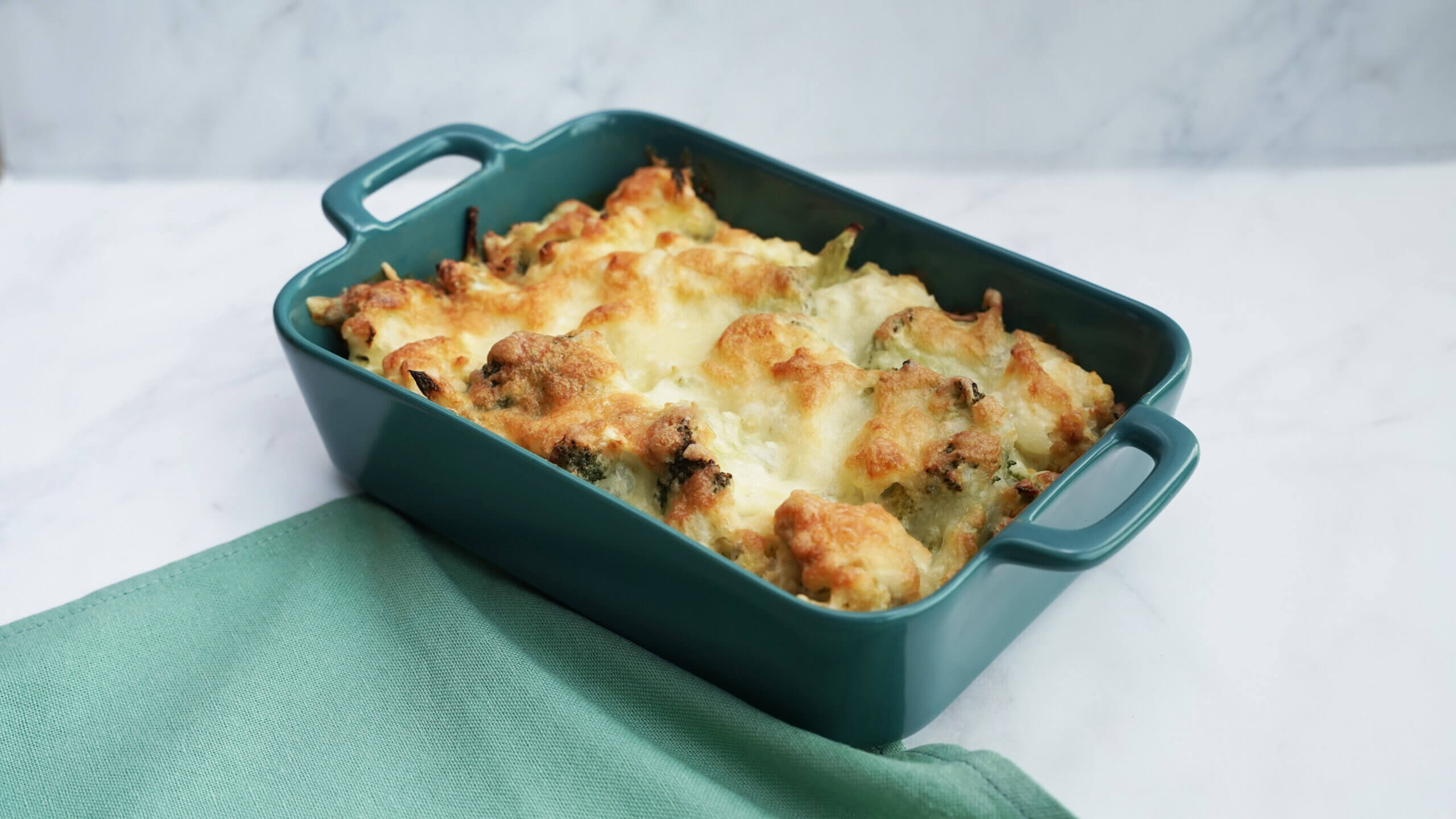 vegetable au gratin in a blue container on a light blue napkin over a light background