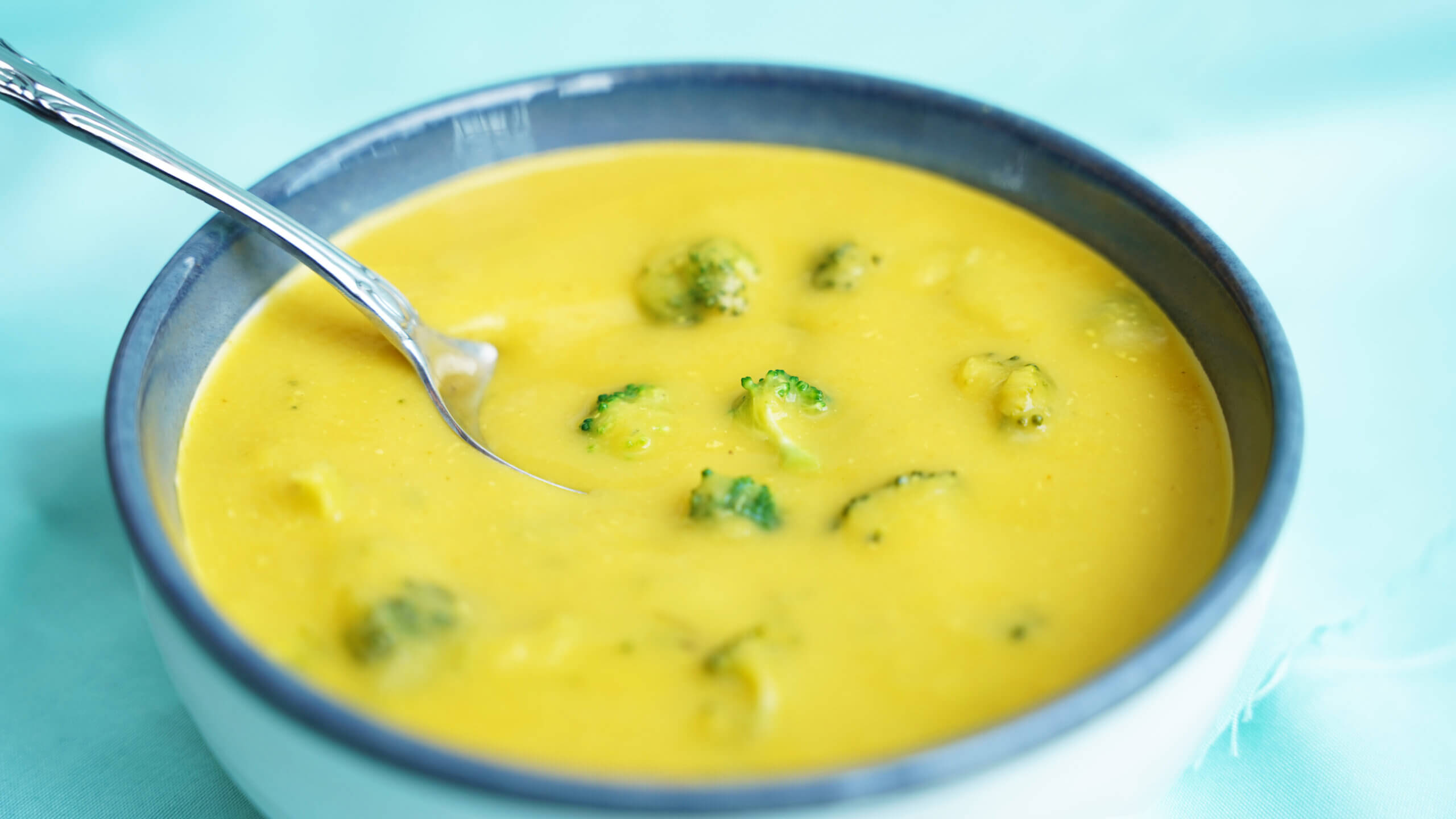 Vegan Broccoli Cheddar Soup with spoon inside less zoom