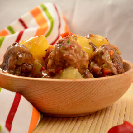 Sweet N Sour Meatballs in a wooden bowl next to a colorful towel