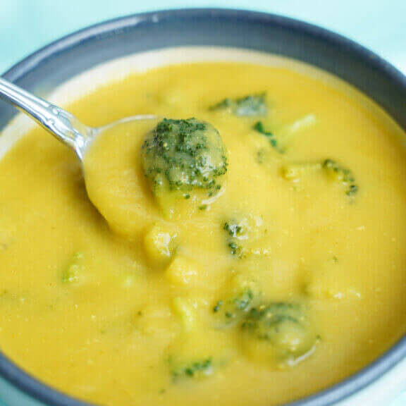 Vegan Broccoli Cheddar Soup with spoon inside zoomed in