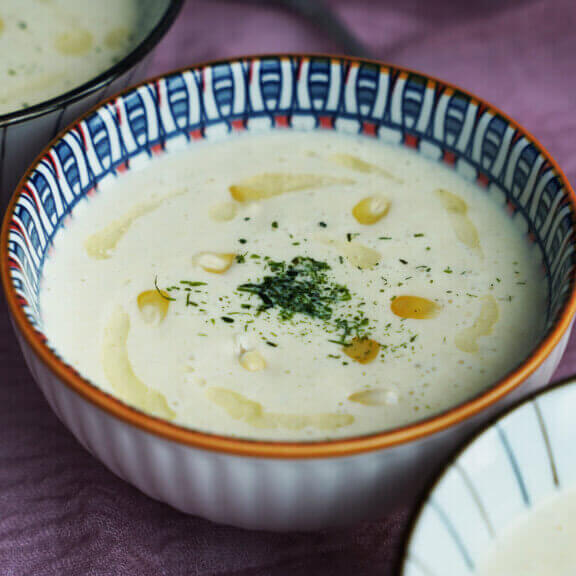 Three bowls of Low Carb Cauliflower Corn Chowder garnished with parsley and a drizzle of olive oil