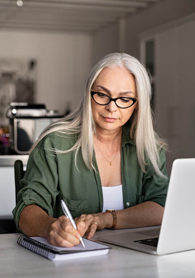 woman at her laptop taking notes